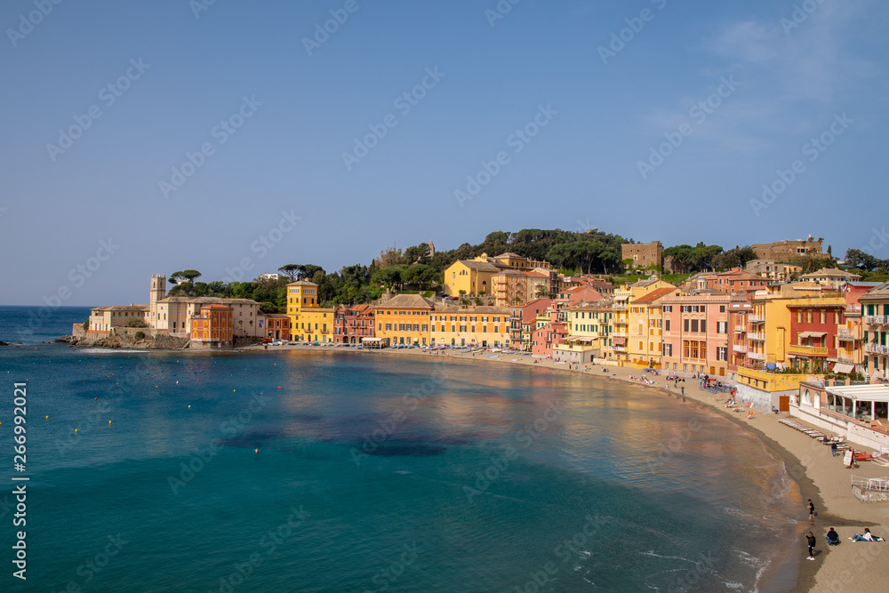 Elevated, panoramic view of the Bay of Silence in the ancient fishing village of Sestri Levante with the typical colored houses on the sandy beach in a sunny day with clear blue sky, Liguria, Italy