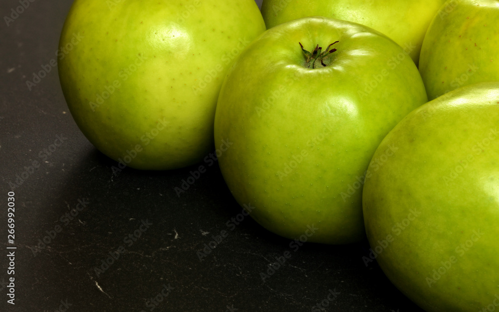 Closeup of green apples on black board Closeup of green apples on black board