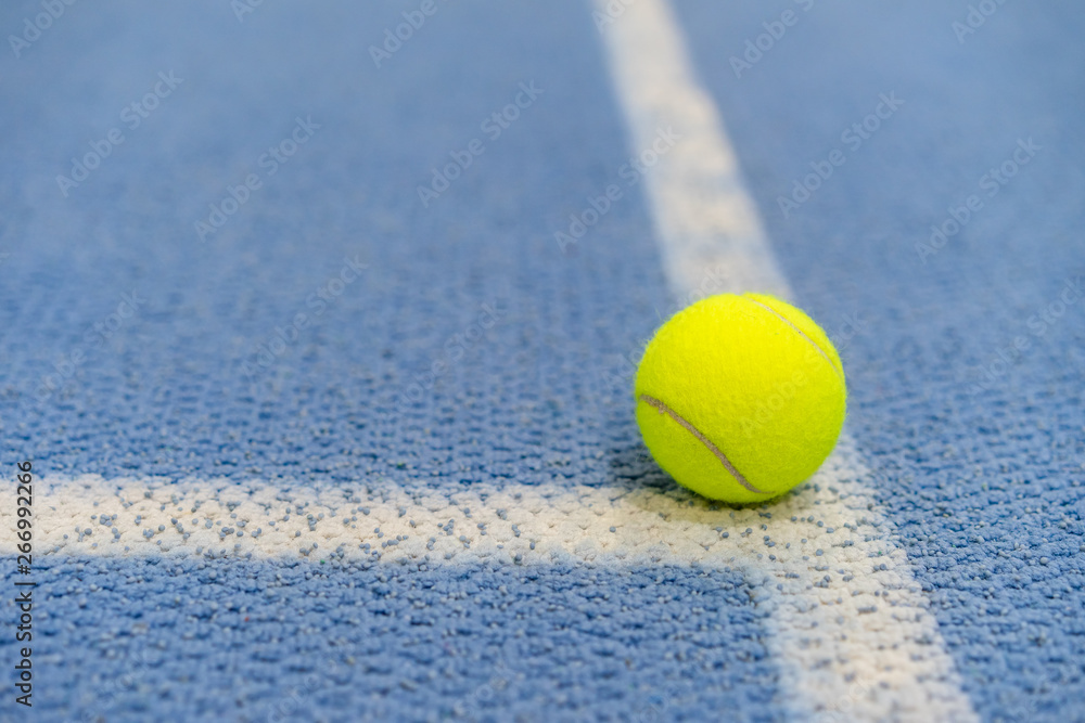 Tennis ball indoor on tennis court, white line, blue surface, copy space