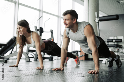 Sporty young couple doing plank exercise in gym