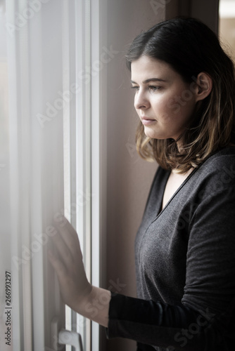 Free Download Niedergeschlagene Frau steht am Fenster und blickt hinaus  - GFXLoad