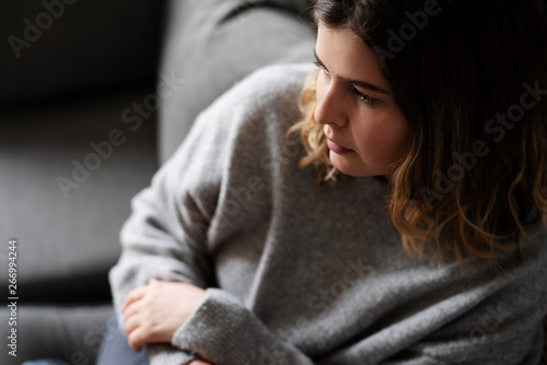 Junge Frau sitzt traurig auf der Couch 