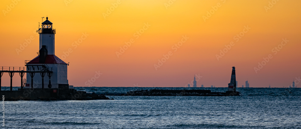 Michigan City, Indiana  : 03/23/2018 / Washington Park Lighthouse during golden hour sunset on the Great Freshwater Lake Michigan with the City of Chicago on the horizon.