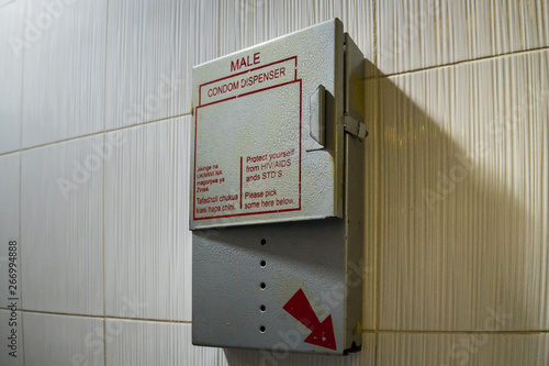 Kisumu, Kenya - March 6. 2019 - empty dispenser for free condoms on a wall in a male toilet in Kisumu airport, Kenya