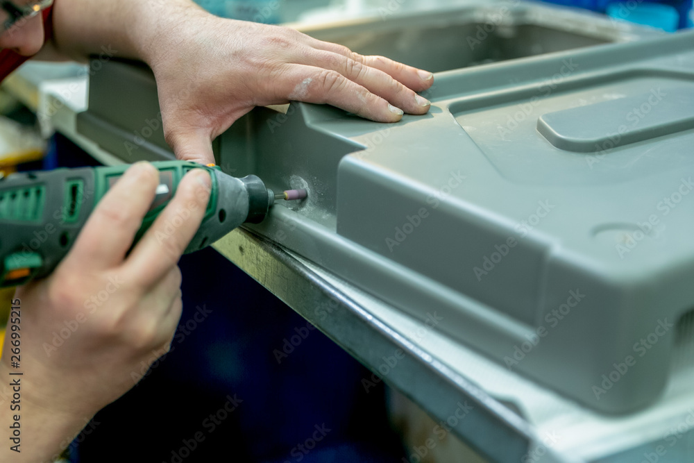 A worker sanding a plastic blank. Manufacturing of plastic products. Medium business concept. Hands close-up