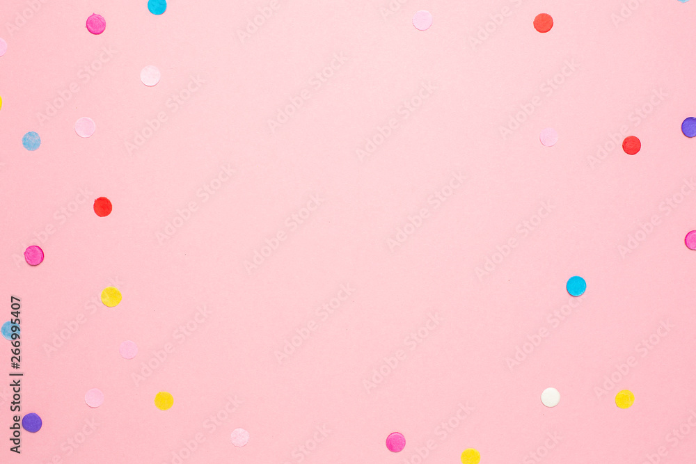 Multi-colored confetti on pink color paper background with space for text . Flat lay composition for birthday , mother day or wedding.