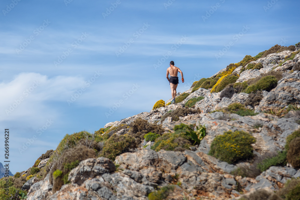 Running people - male runner at sunset in mountain. Man athlete jogging training for marathon trail run in beautiful amazing landscape nature above the clouds. Fit shirtless male cross country runner.