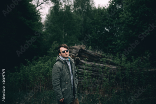 portrait of a young stylish man in round sunglasses in the forest