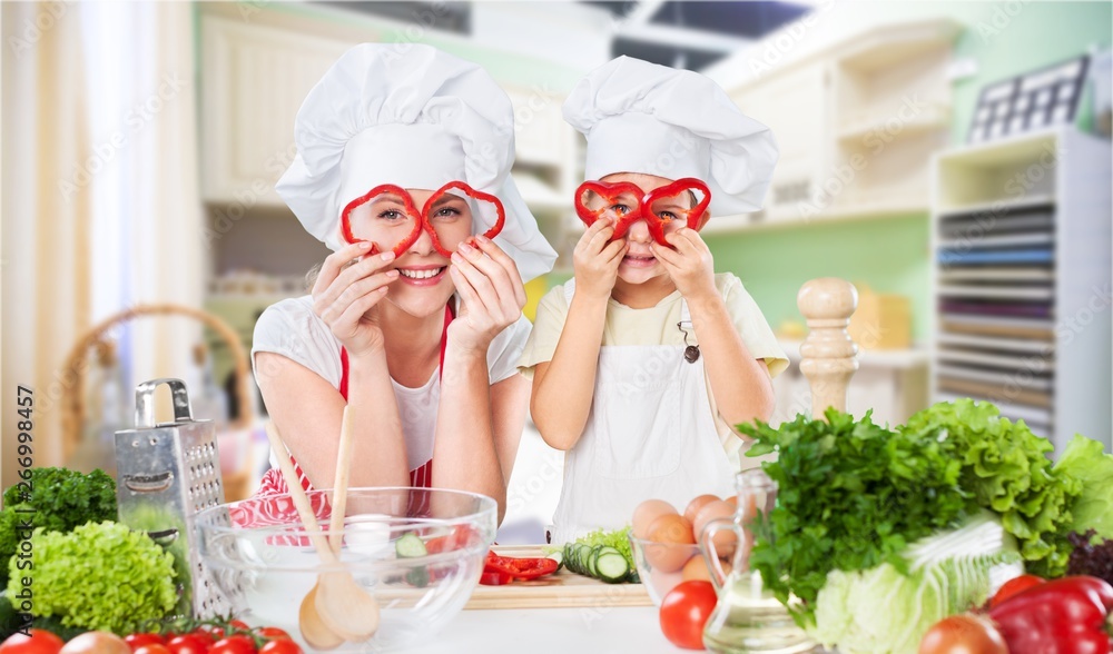 Portrait of adorable little girl and her mother cooking together Portrait of adorable little girl and her mother cooking together