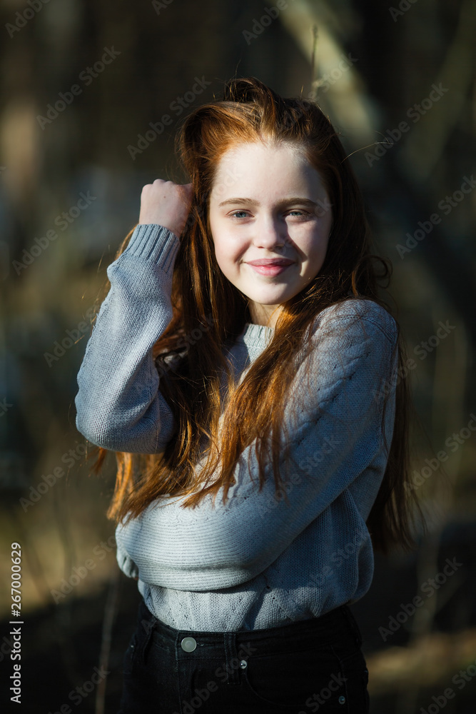 Portrait of attractive cheerful teen girl with bright red long hair, photoshooting in the spring Park. Portrait of attractive cheerful teen girl with bright red long hair, photoshooting in the spring Park.