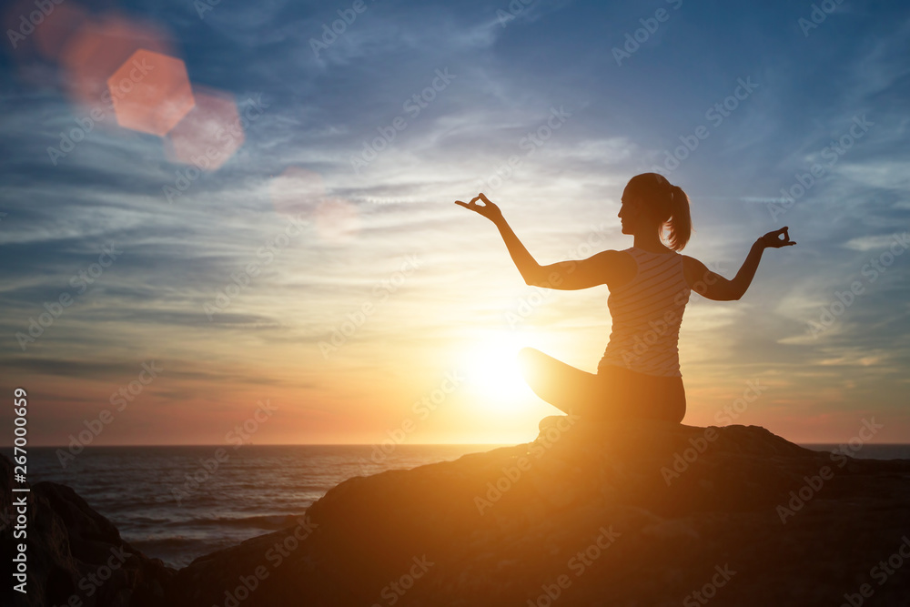 Yoga silhouette of meditation woman on the beach at amazing sunset.