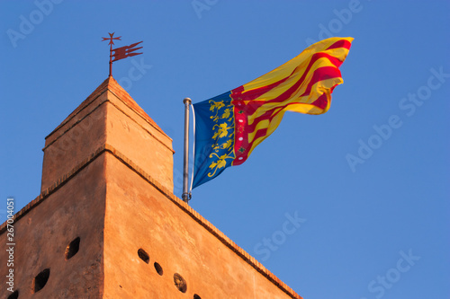 Bilde på lerret Flag of the Comunitat Valenciana atop a historic building