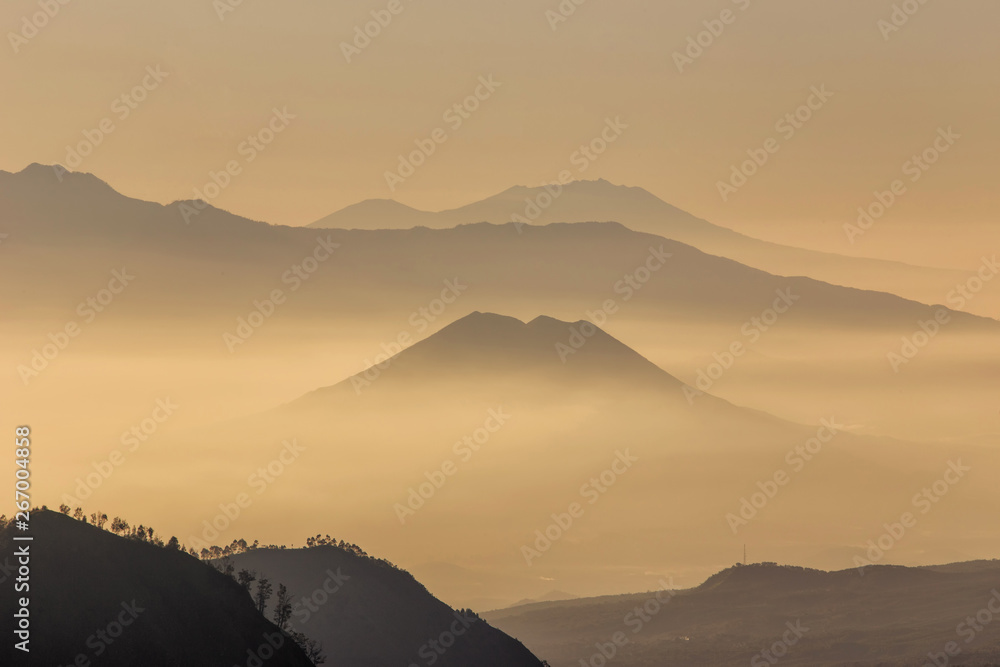 Mountain range with visible silhouettes through the morning yellowish fog.