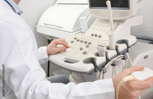 Sonographer operating modern ultrasound machine in clinic, closeup photo