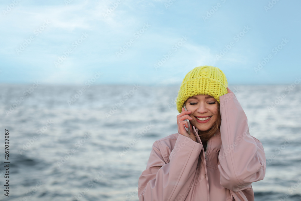 Young woman talking on mobile phone near sea Young woman talking on mobile phone near sea