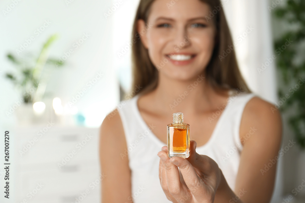 Fototapeta premium Young woman holding eyelash oil indoors, closeup