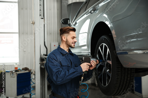Technician working with car in automobile repair shop