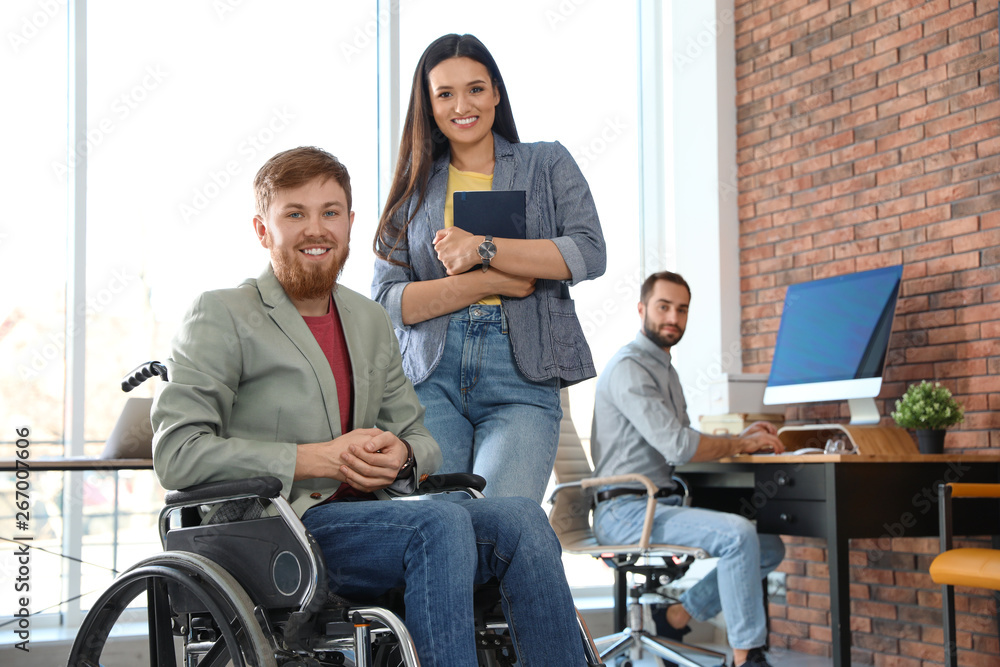 Young man in wheelchair with colleagues at office Young man in wheelchair with colleagues at office