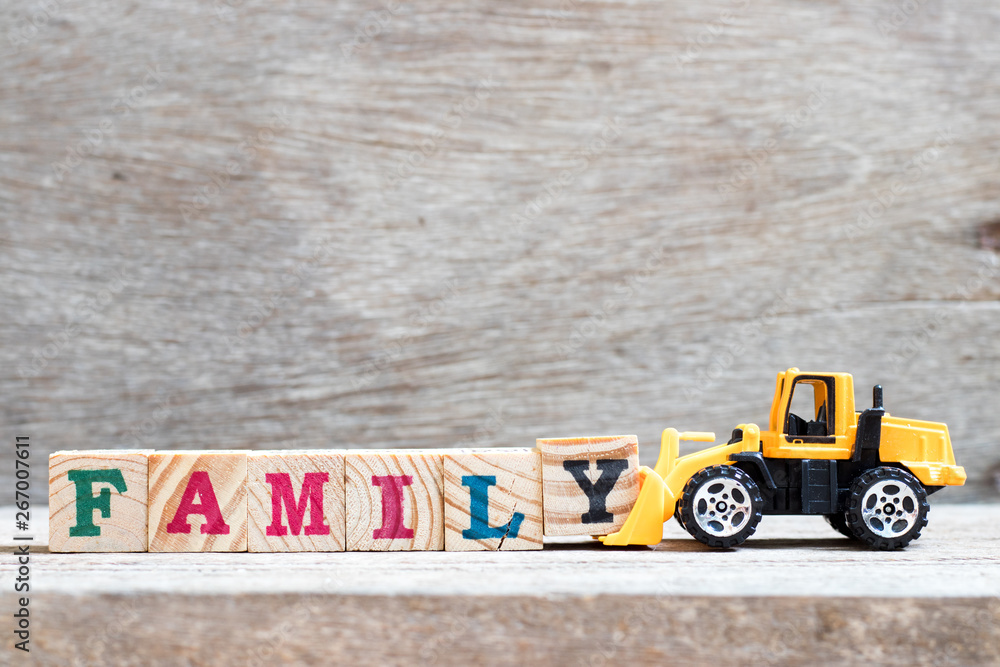 Obraz premium Toy bulldozer hold letter block y to complete word family on wood background