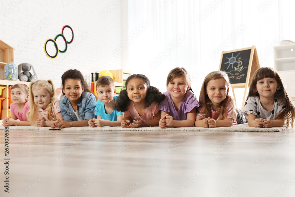 Group of cute little children lying on floor indoors. Kindergarten playtime activities