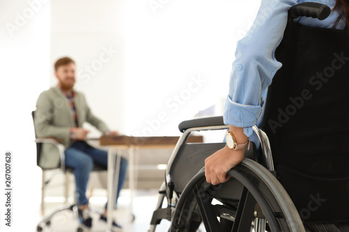 Young woman in wheelchair with colleague at office, closeup © New Africa