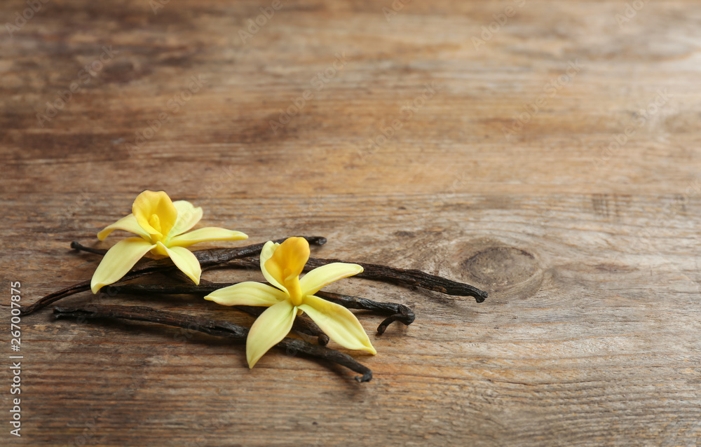 Vanilla sticks and flowers on wooden background. Space for text Vanilla sticks and flowers on wooden background. Space for text