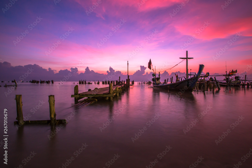 Fototapeta premium The blurred background of the morning twilight by the sea, changing the color of the beautiful sky, there is a fishing boat docked waiting to go out to find fish again.