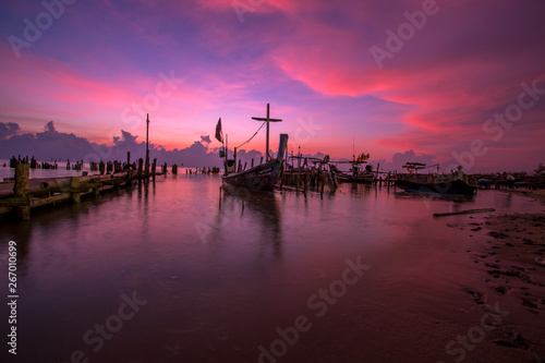 The blurred background of the morning twilight by the sea, changing the color of the beautiful sky, there is a fishing boat docked waiting to go out to find fish again.