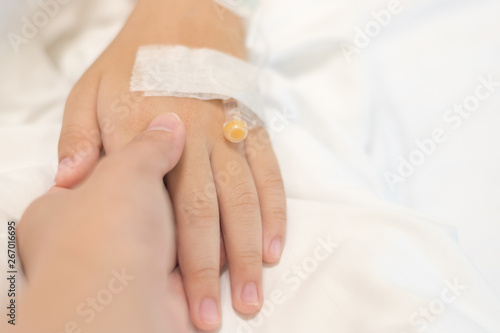 Child patient with IV line in hand sleep on hospital bed with mother's hand holding together to support ill daughter.Medical palliation healthcare concept 