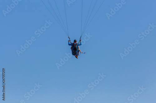 Tandem paragliders floating across blue sky suspended on the equipment