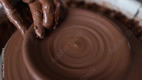 Clay turned on potters wheel by artist's hands photo