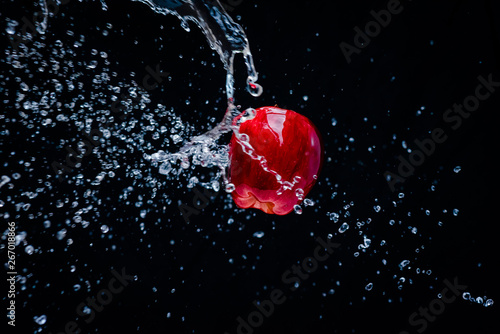 A red apple in splash of water isolated on black background.