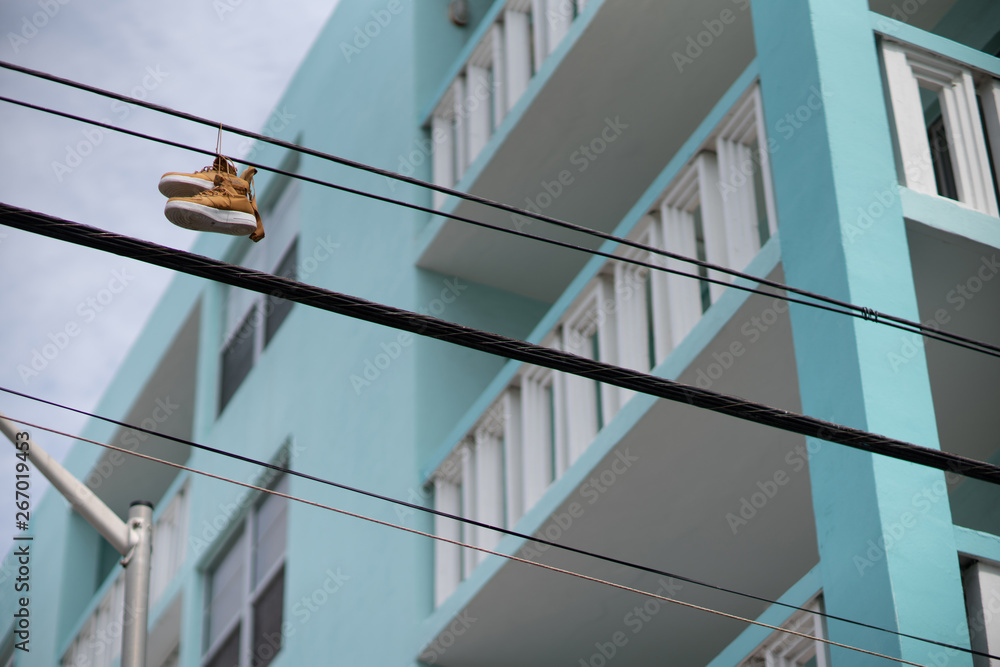 Fototapeta premium Sneakers shoes hanging from power lines