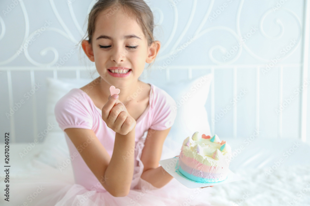 Cute little child girl in pink dress was holding pink heart chocolate from birthday cake to eat on the bedroom background. Cute little child girl in pink dress was holding pink heart chocolate from birthday cake to eat on the bedroom background.