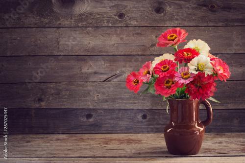 flowers in vase on old wooden background