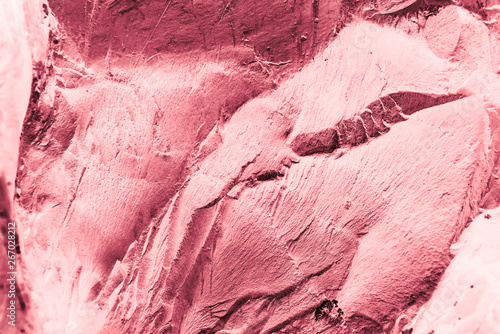 Vintage pink background. Rough painted wall of fiesta color. Imperfect plane of rosy colored. Uneven old decorative toned backdrop of rouge tint. Texture of pink hue. Ornamental stony surface. photo