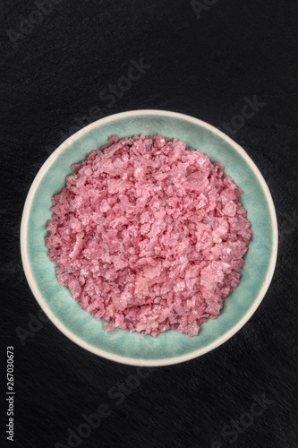 A bowl of pink Himalayan sea salt, shot from above on a black background with copy space