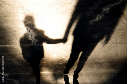 Shadow silhouettes of father and son walking hand in hand