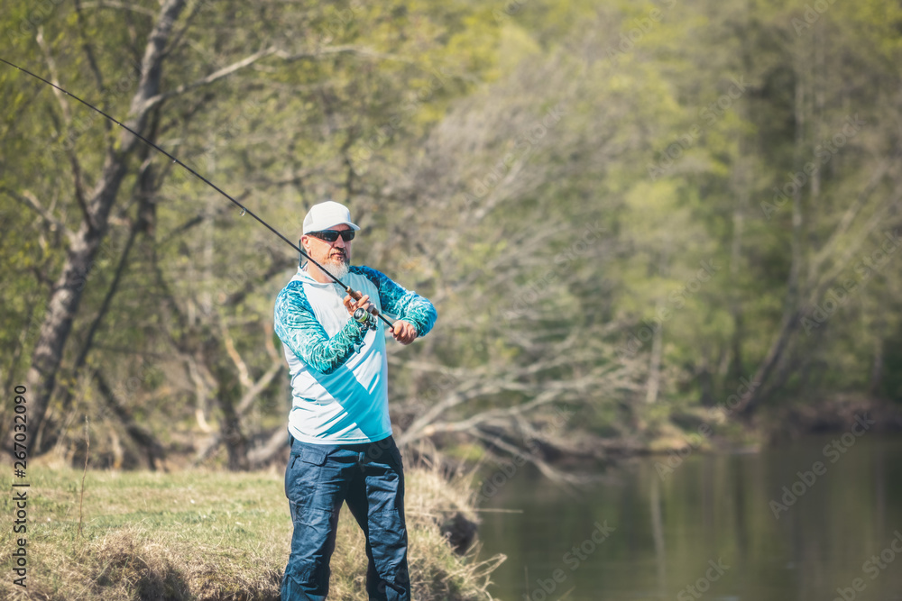 Fisherman with a spinning rod catching fish on a river Fisherman with a spinning rod catching fish on a river