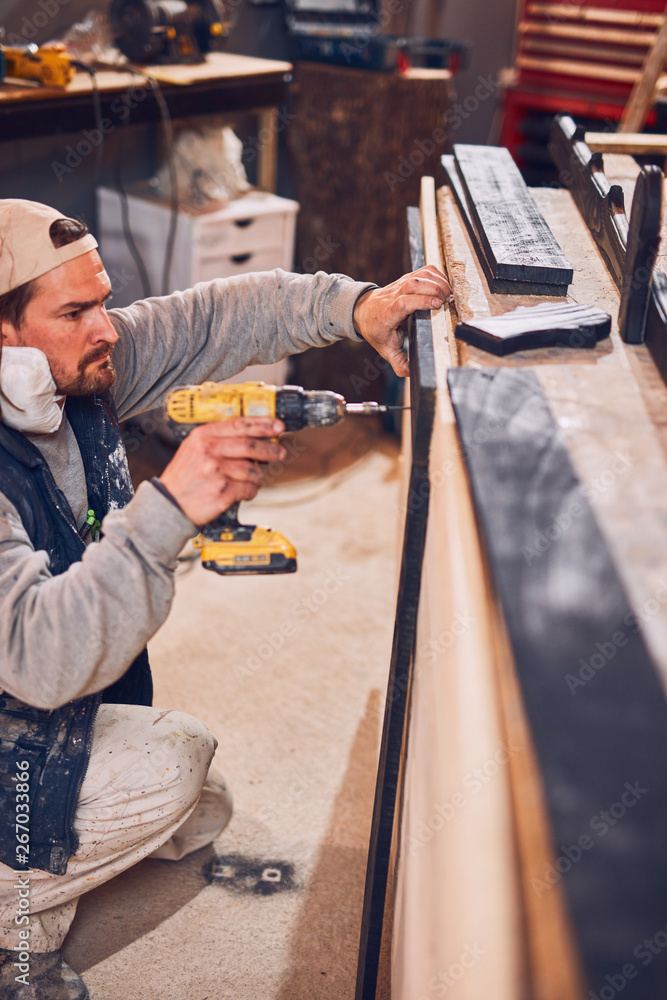 Male carpenter working on old wood in a retro vintage workshop. Male carpenter working on old wood in a retro vintage workshop.