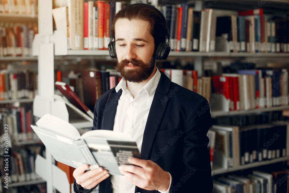 Man in a library. Guy in a black suit. Student with a books.