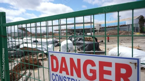 Danger construction sign in front of construction siteA plastic sign on a fence that cordons off a construction site stating Danger, it's a construction site and no trespassing because it's dangerous. photo