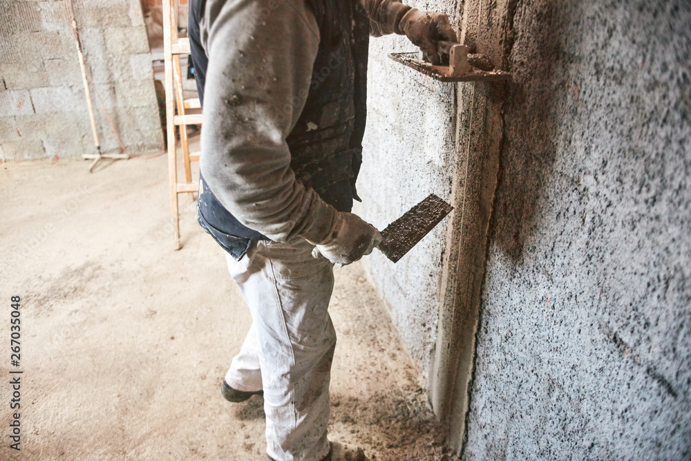 Real construction worker making a wall inside the new house.