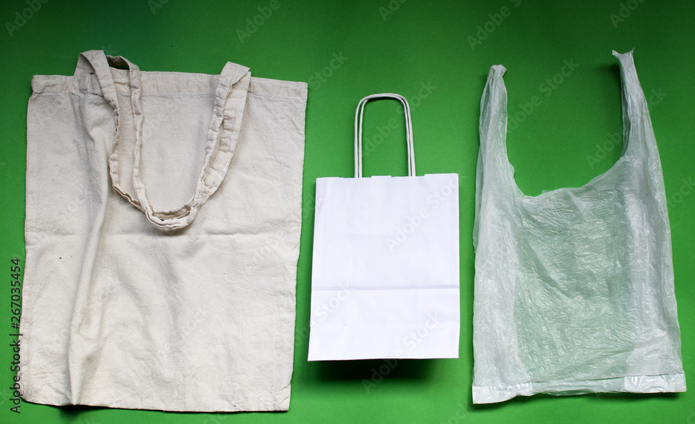Natural reusable linen fabric and white paper bags for shopping VS plastic bags. Eco friendly lifestyle. No pollution choice concept. Natural reusable linen fabric and white paper bags for shopping VS plastic bags. Eco friendly lifestyle. No pollution choice concept.