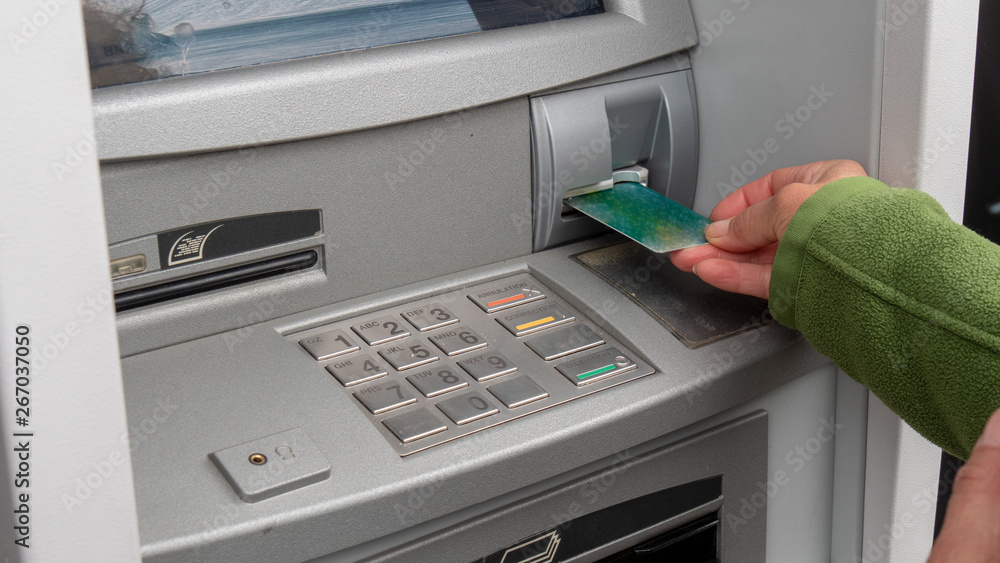 Hand of woman with a credit card, using an ATM Hand of woman with a credit card, using an ATM
