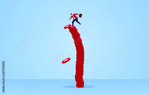 Businessman standing on a pile of tall gold coins shaking