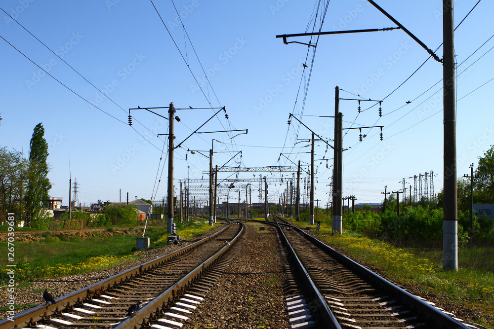 Rail way on country side in summer with a lot of electric poles on it sides on blue sky background