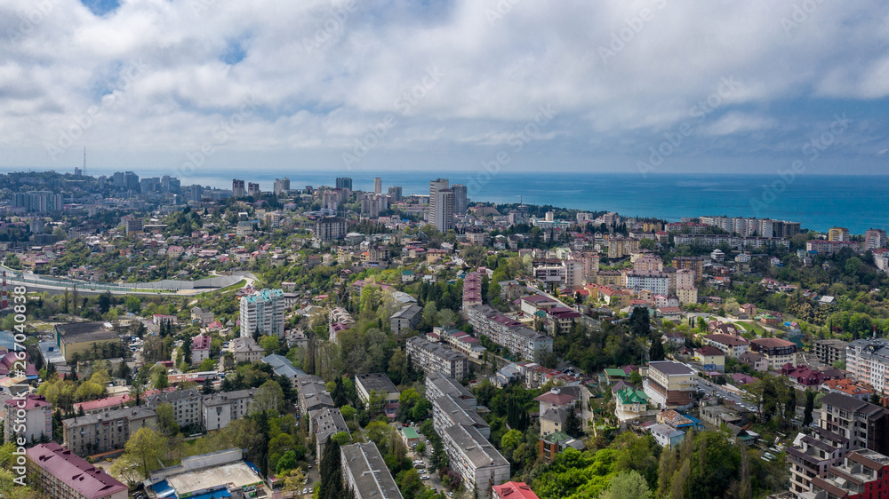 Naklejka premium Aerial photography. Urban infrastructure. Dense building. Residential building. Sea view from the window. Coastal town. High-rise buildings on the mountain. The black sea coast of Sochi, Russia.