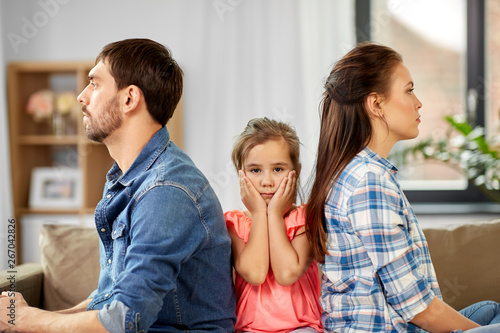 family problem, divorce and people concept - unhappy father, mother and sad little daughter at home photo