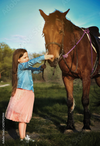 Cute girl on grass with horse. Friendship concept image.